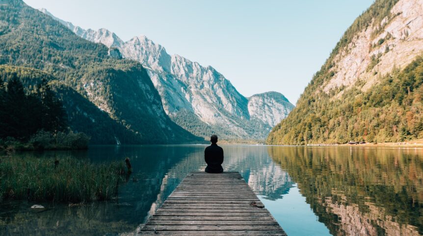 A man sitting in front of a lake relaxing, hosted by Wellin5.