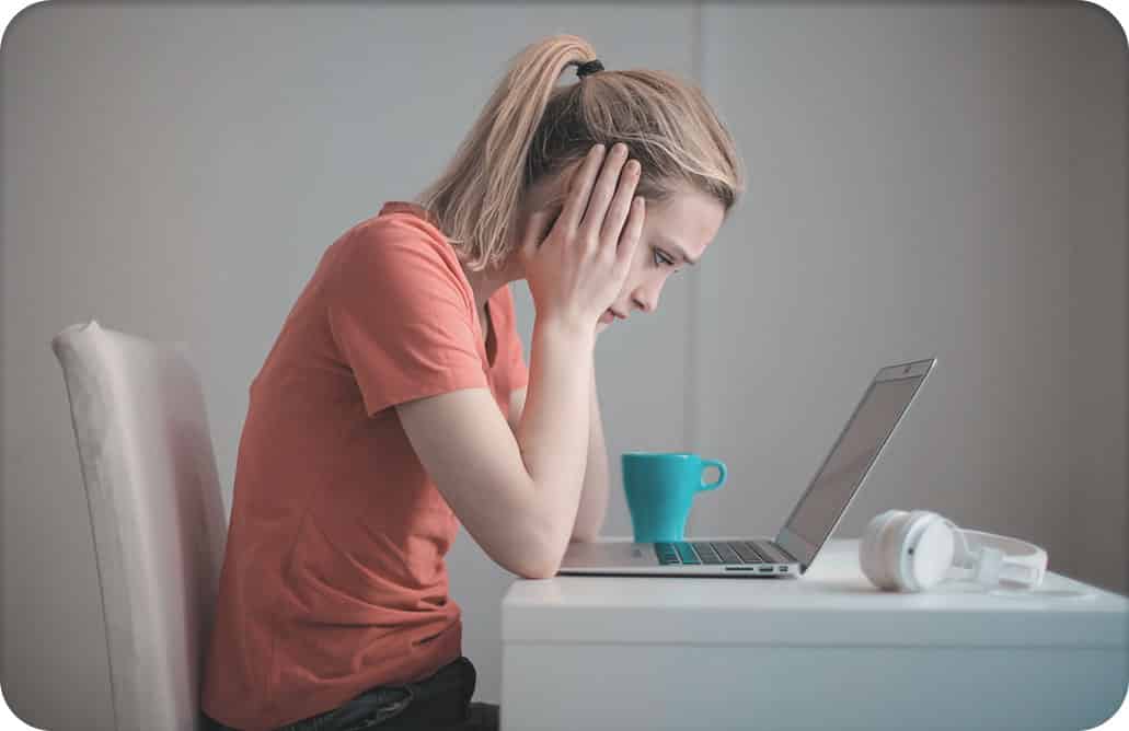 Woman staring at laptop screen, holding head in hands