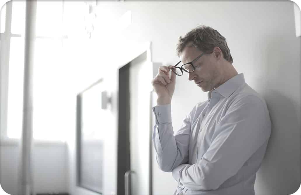 Man standing in hallway, holding his glasses