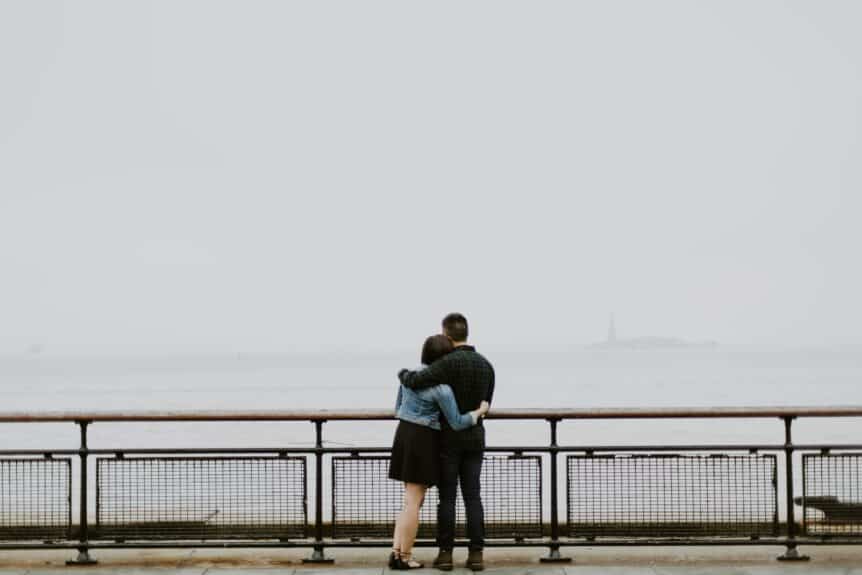 A couple standing and embracing in front of a foggy ocean