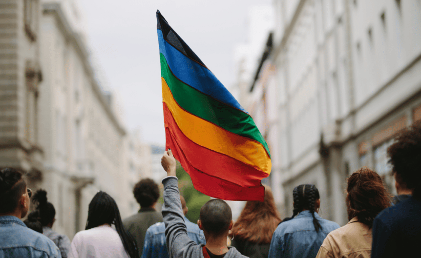 A rainbow flag held aloft at a Pride parade.